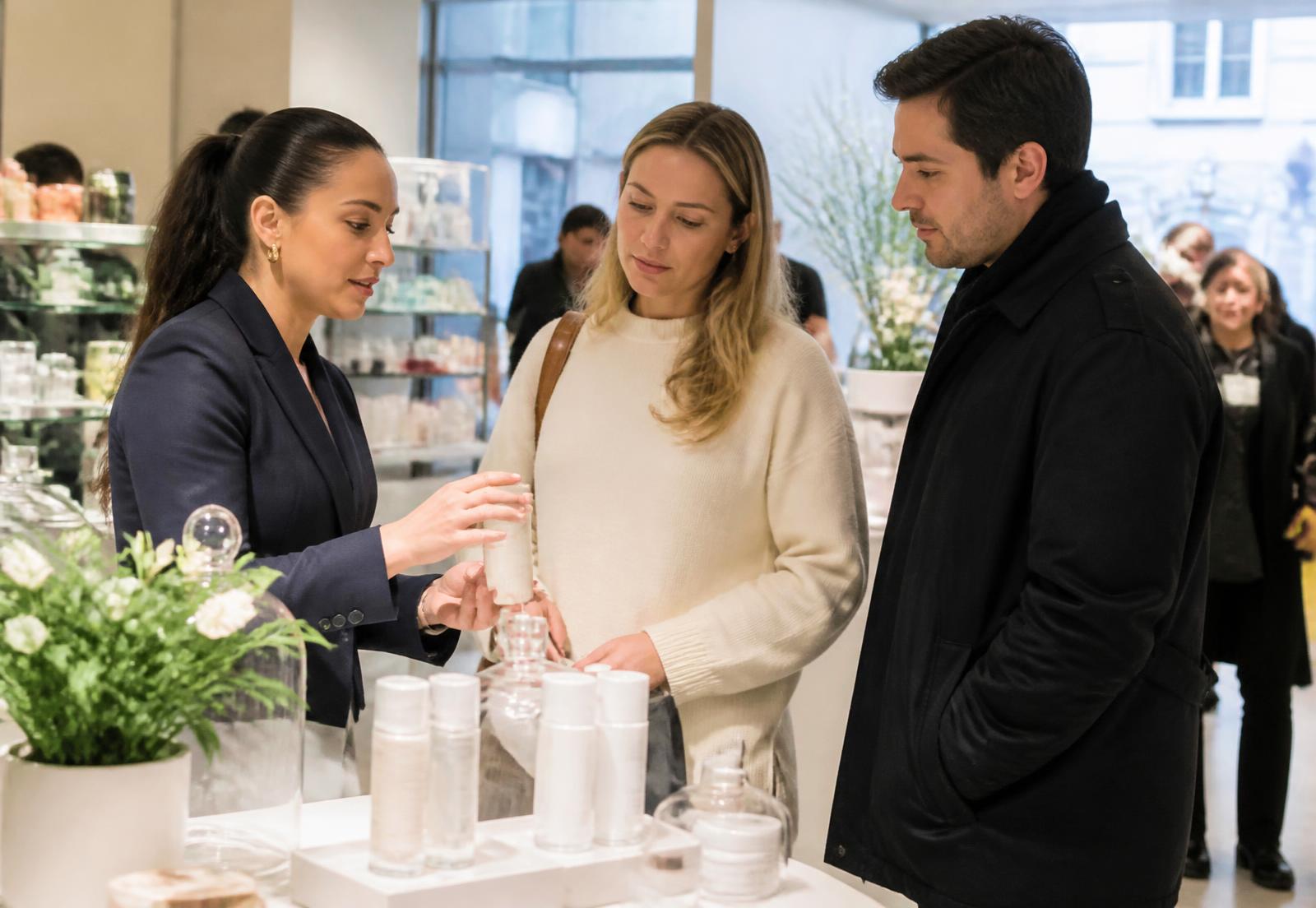 Brand ambassador demonstrating a product to two shoppers inside a bright New York store